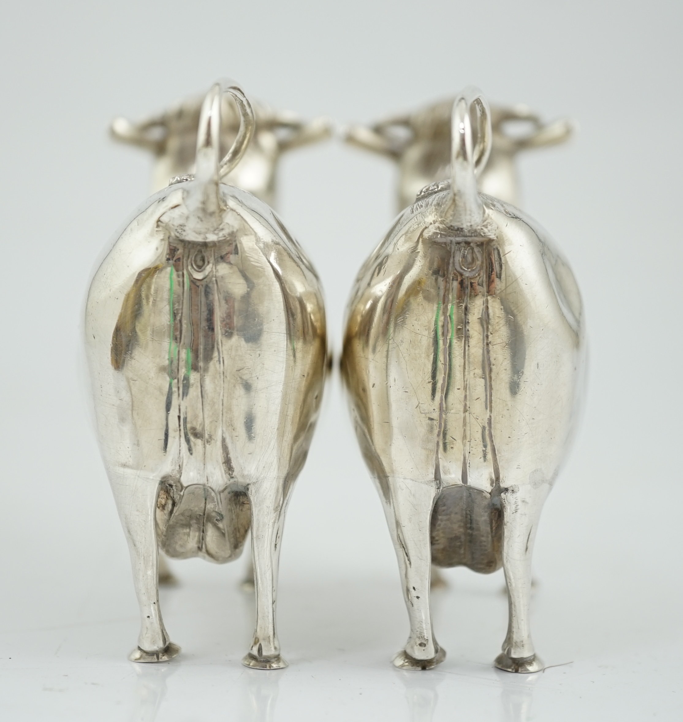 A pair of Elizabeth II silver cow creamers, by Heming & Co